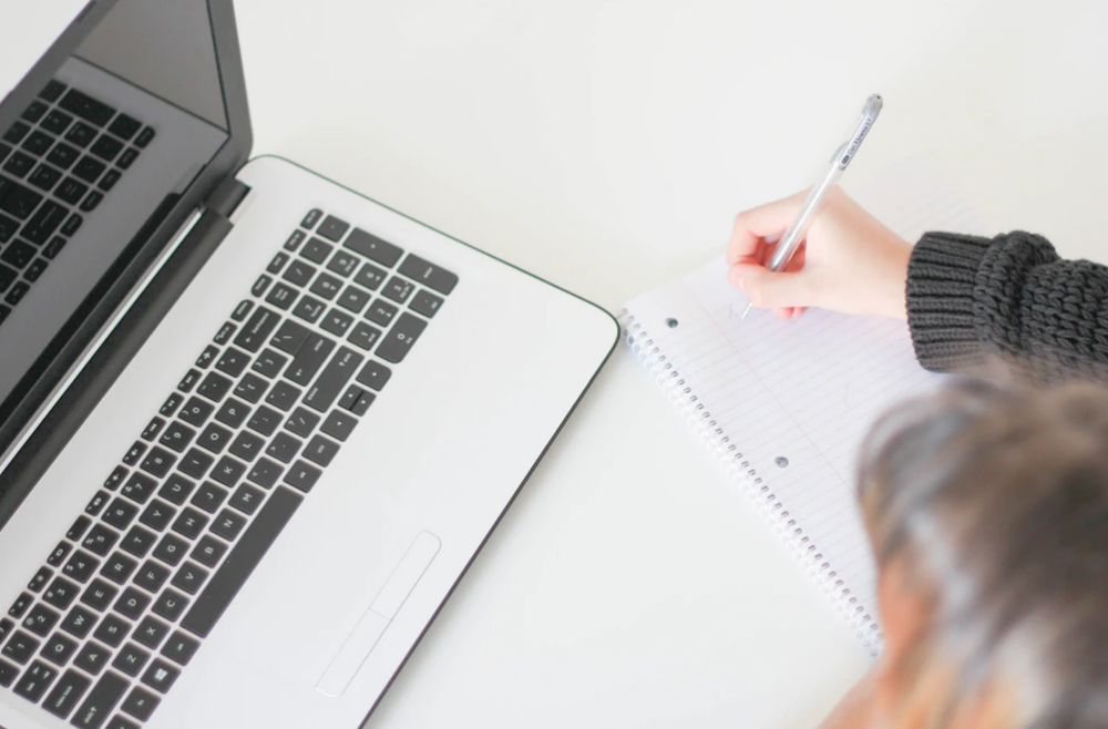 laptop, person writing in notebook, applying for bursaries